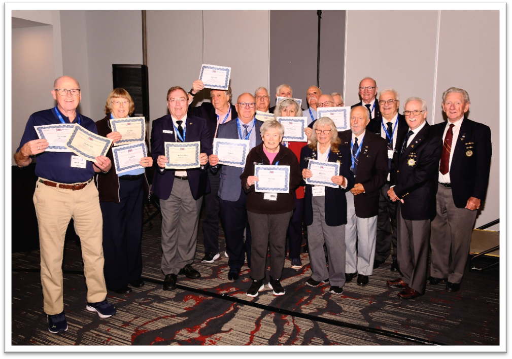 Large group of men and women happily holding up certificates