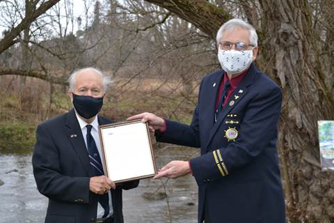 Two men wearing formal attire while holding up certificate outside